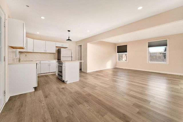 kitchen featuring decorative light fixtures, light hardwood / wood-style flooring, white cabinets, white fridge, and a kitchen island