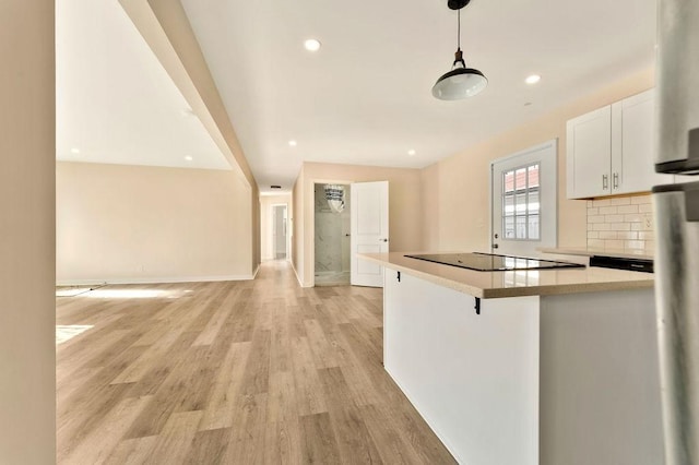 kitchen with a kitchen breakfast bar, backsplash, black electric cooktop, white cabinets, and light wood-type flooring