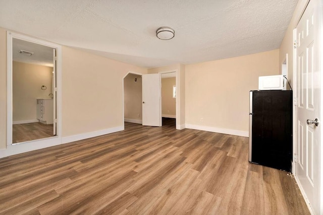 empty room featuring a textured ceiling and light wood-type flooring