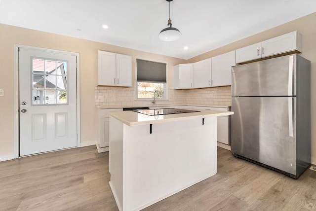 kitchen with a kitchen island, decorative light fixtures, light hardwood / wood-style floors, white cabinetry, and stainless steel refrigerator