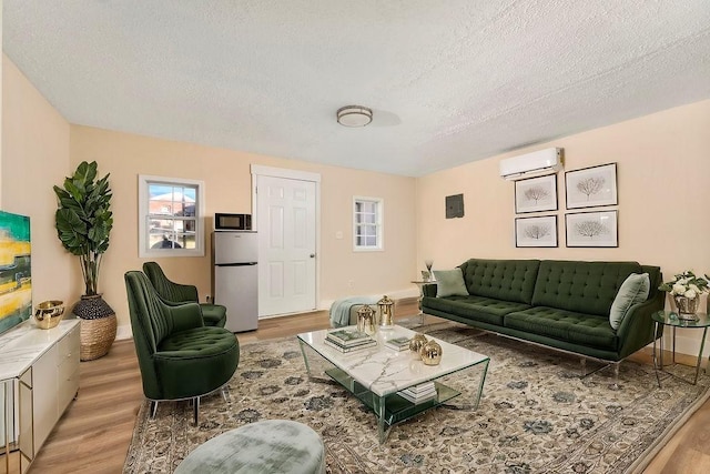 living room featuring a textured ceiling, light hardwood / wood-style floors, and a wall mounted air conditioner