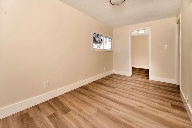 unfurnished room with light hardwood / wood-style flooring and a textured ceiling