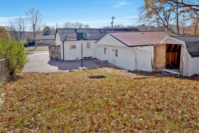 rear view of property featuring a storage unit, a patio area, and a yard