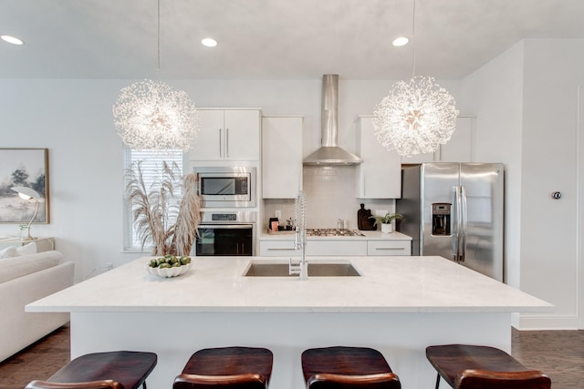 kitchen with a chandelier, appliances with stainless steel finishes, decorative light fixtures, and wall chimney exhaust hood