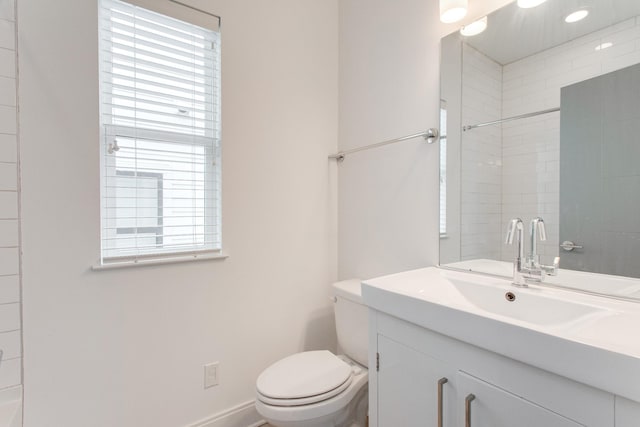 bathroom featuring toilet, vanity, and tiled shower