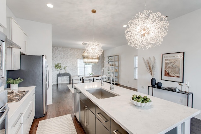 kitchen with white cabinetry, a center island with sink, hanging light fixtures, and appliances with stainless steel finishes