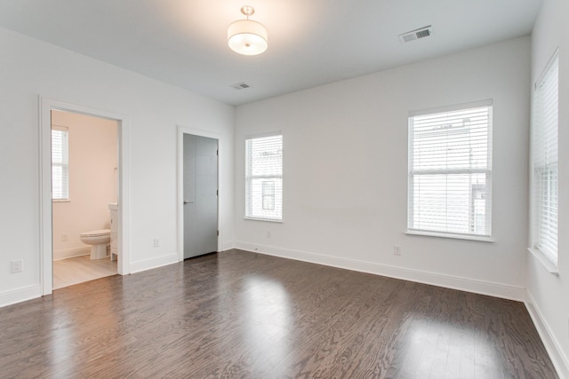 unfurnished bedroom with ensuite bath and dark hardwood / wood-style floors