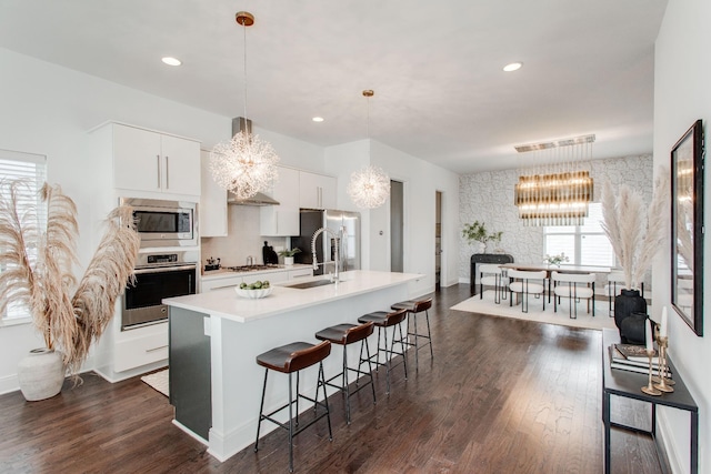 kitchen with hanging light fixtures, sink, an island with sink, appliances with stainless steel finishes, and white cabinetry