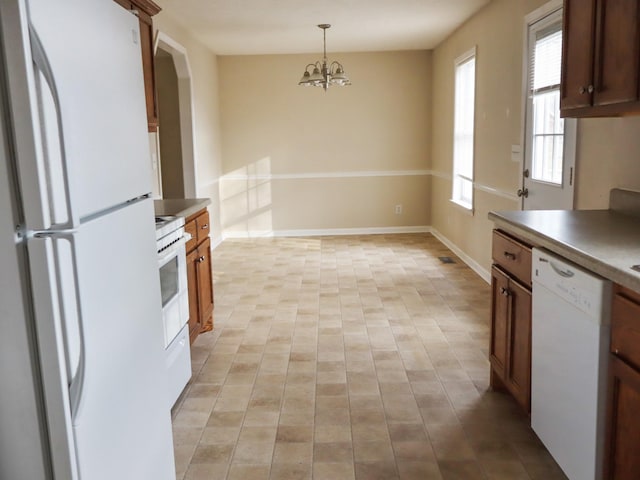 kitchen featuring decorative light fixtures, white appliances, and a chandelier