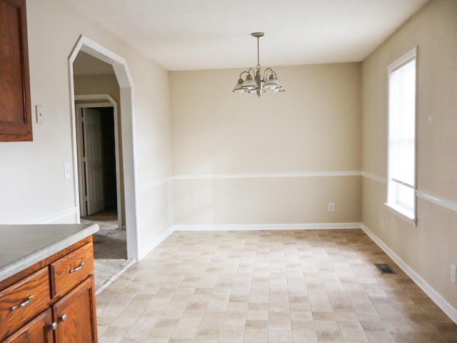 unfurnished dining area featuring a wealth of natural light and a notable chandelier