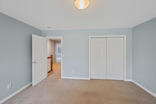 unfurnished bedroom featuring a closet and light colored carpet