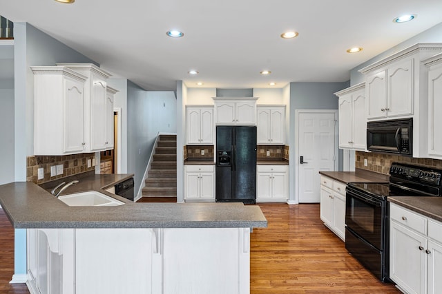 kitchen with sink, tasteful backsplash, a kitchen breakfast bar, light hardwood / wood-style floors, and black appliances