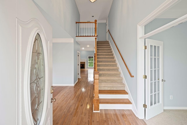 staircase with hardwood / wood-style floors and crown molding