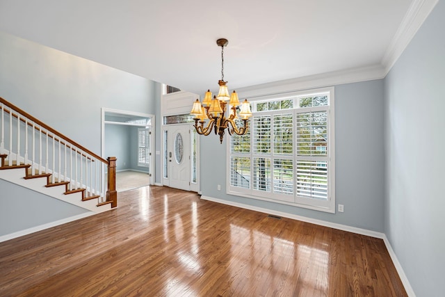 interior space featuring ornamental molding, wood-type flooring, and a notable chandelier