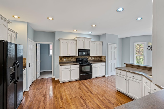 kitchen with black appliances, decorative backsplash, light hardwood / wood-style floors, and white cabinets