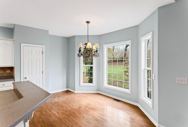 unfurnished dining area with hardwood / wood-style floors and an inviting chandelier