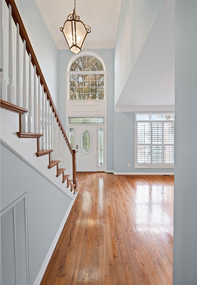 entryway featuring a high ceiling, light hardwood / wood-style floors, and a notable chandelier