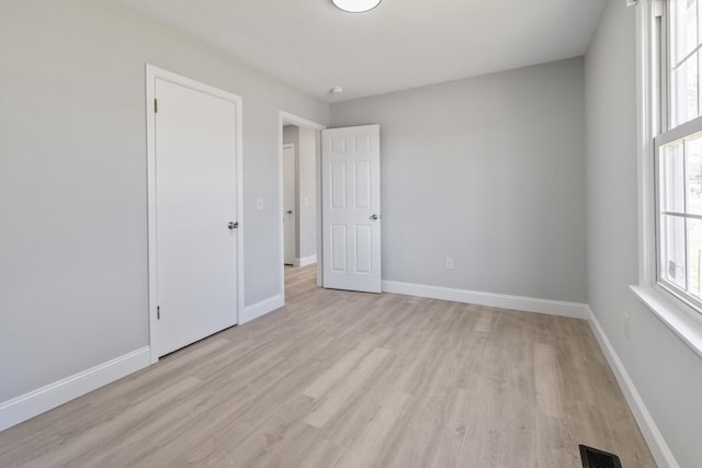 spare room featuring baseboards, visible vents, and light wood-style floors