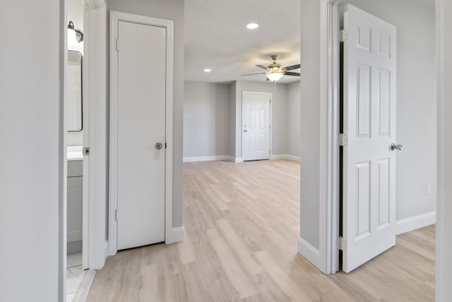 hall featuring light wood-type flooring, baseboards, and recessed lighting