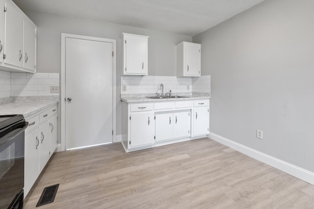 kitchen with light countertops, visible vents, black electric range oven, white cabinets, and a sink