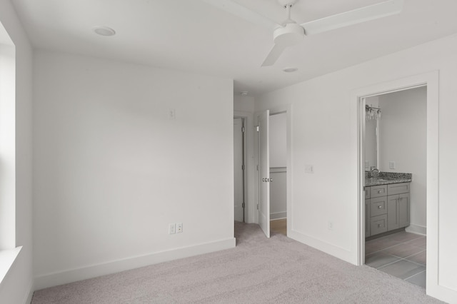 unfurnished bedroom with light carpet, ensuite bathroom, ceiling fan, and sink