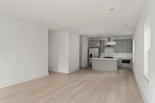 kitchen featuring appliances with stainless steel finishes, tasteful backsplash, gray cabinetry, a kitchen island, and hanging light fixtures