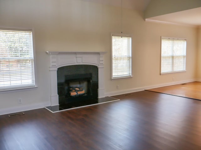 unfurnished living room featuring dark hardwood / wood-style floors, a wealth of natural light, and vaulted ceiling