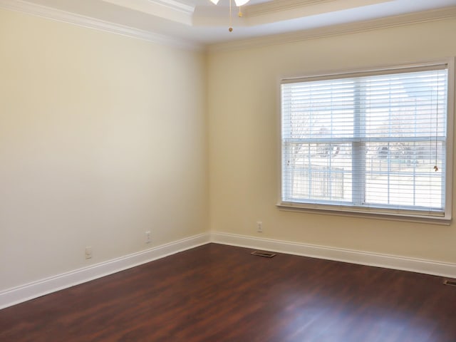 spare room featuring dark hardwood / wood-style floors, a tray ceiling, crown molding, and ceiling fan