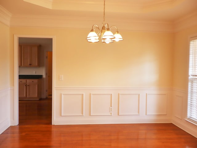 spare room with ornamental molding, dark wood-type flooring, a wealth of natural light, and an inviting chandelier