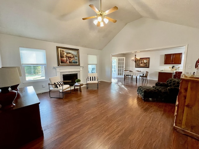 living room with high vaulted ceiling, dark wood-type flooring, and ceiling fan with notable chandelier