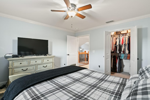 carpeted bedroom with a spacious closet, ceiling fan, a closet, and crown molding