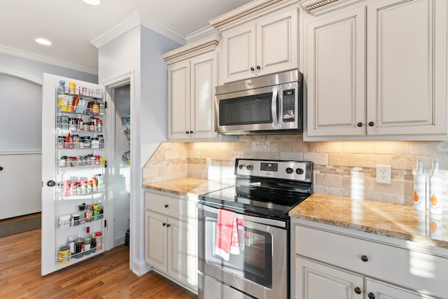 kitchen with backsplash, crown molding, light hardwood / wood-style flooring, stainless steel appliances, and light stone counters