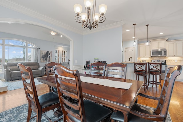 dining room with light hardwood / wood-style floors, crown molding, and an inviting chandelier