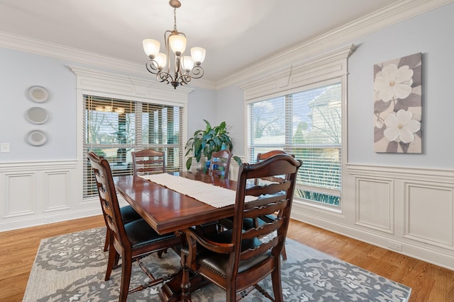 dining space with hardwood / wood-style floors, crown molding, and a notable chandelier