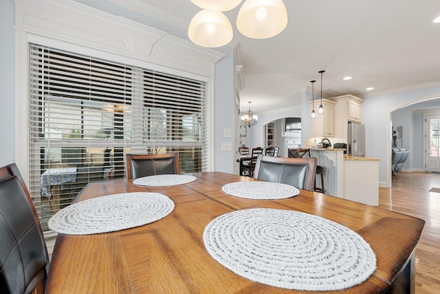 dining area featuring light wood-type flooring, a notable chandelier, and crown molding