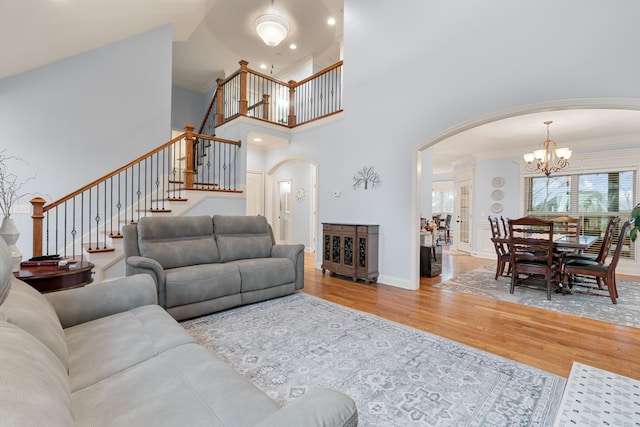 living room featuring a notable chandelier, crown molding, a towering ceiling, and hardwood / wood-style flooring