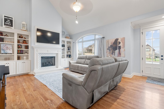 living room with ceiling fan, light wood-type flooring, a fireplace, and vaulted ceiling