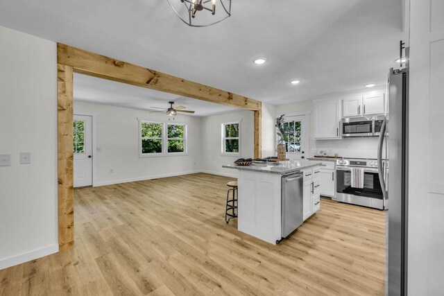 kitchen with a breakfast bar area, a kitchen island, light hardwood / wood-style floors, white cabinetry, and stainless steel appliances