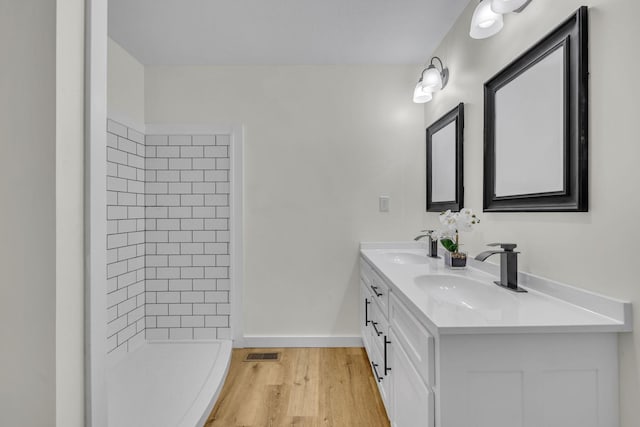 bathroom featuring hardwood / wood-style floors, vanity, and tiled shower