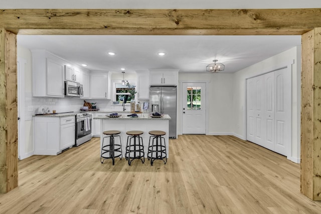 kitchen with a kitchen bar, a center island, stainless steel appliances, and light wood-type flooring