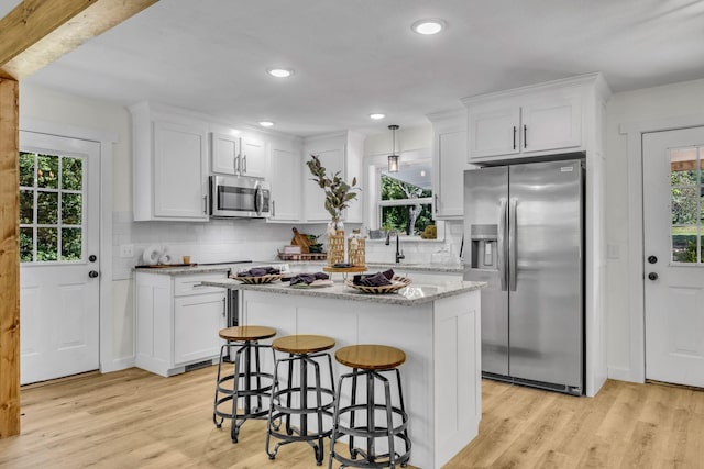 kitchen with white cabinets, light wood-type flooring, and appliances with stainless steel finishes