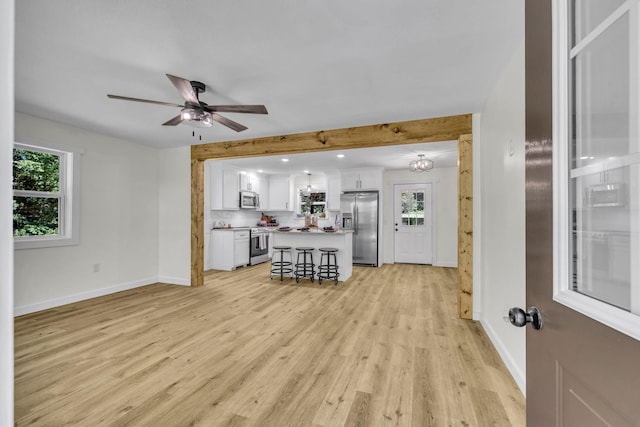 living room featuring ceiling fan with notable chandelier and light wood-type flooring