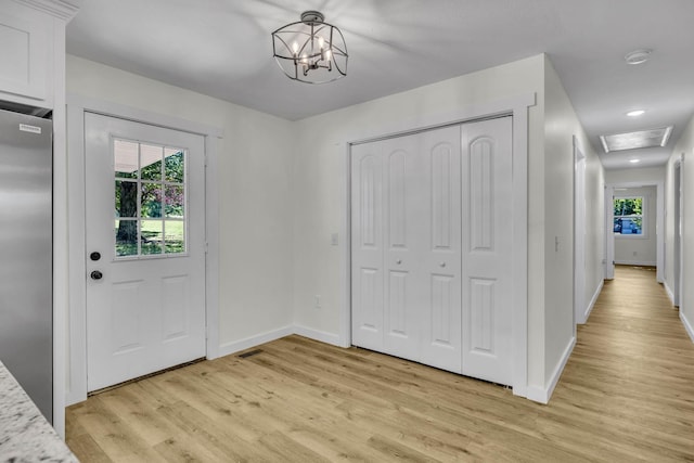 foyer entrance with light hardwood / wood-style floors and an inviting chandelier