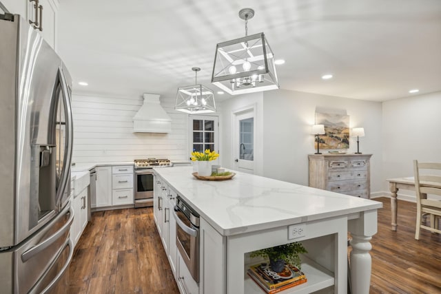 kitchen with hanging light fixtures, stainless steel appliances, white cabinets, a kitchen island, and custom exhaust hood