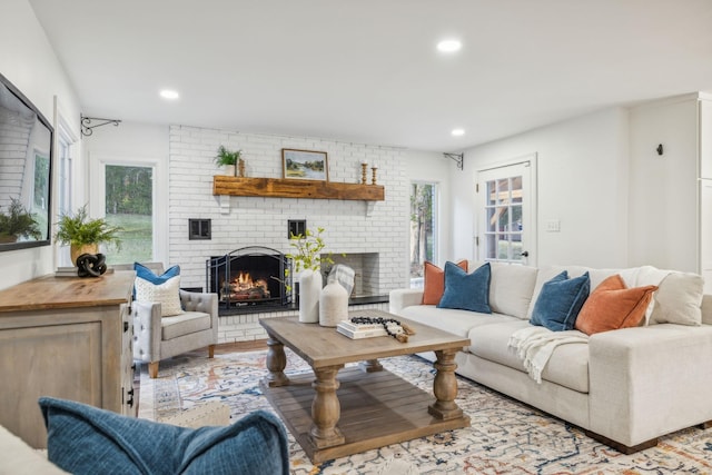 living room featuring a fireplace, a healthy amount of sunlight, and light hardwood / wood-style flooring