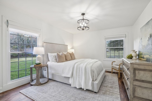 bedroom with an inviting chandelier, light wood-type flooring, and multiple windows