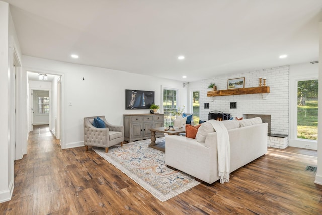 living room with dark hardwood / wood-style flooring and a brick fireplace