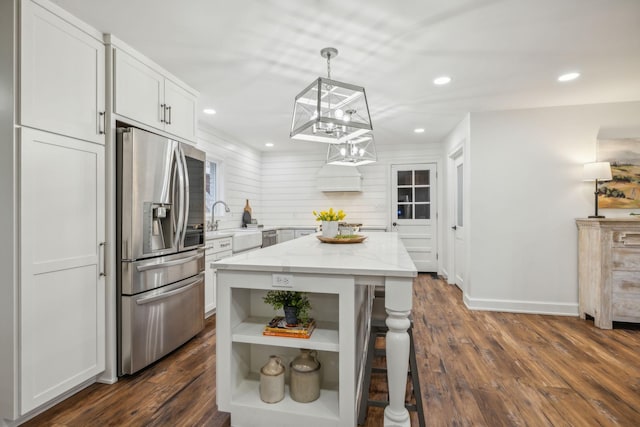 kitchen with hanging light fixtures, stainless steel fridge, a kitchen island, light stone counters, and white cabinetry