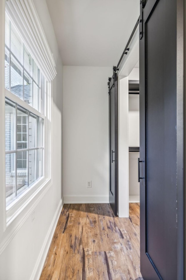 unfurnished bedroom with a barn door and light hardwood / wood-style floors