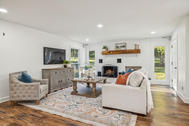 living room featuring dark wood-type flooring and a brick fireplace